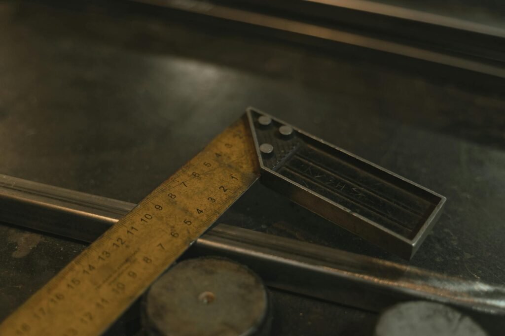 Close-up shot of a metal ruler and measuring tool on a workshop surface.