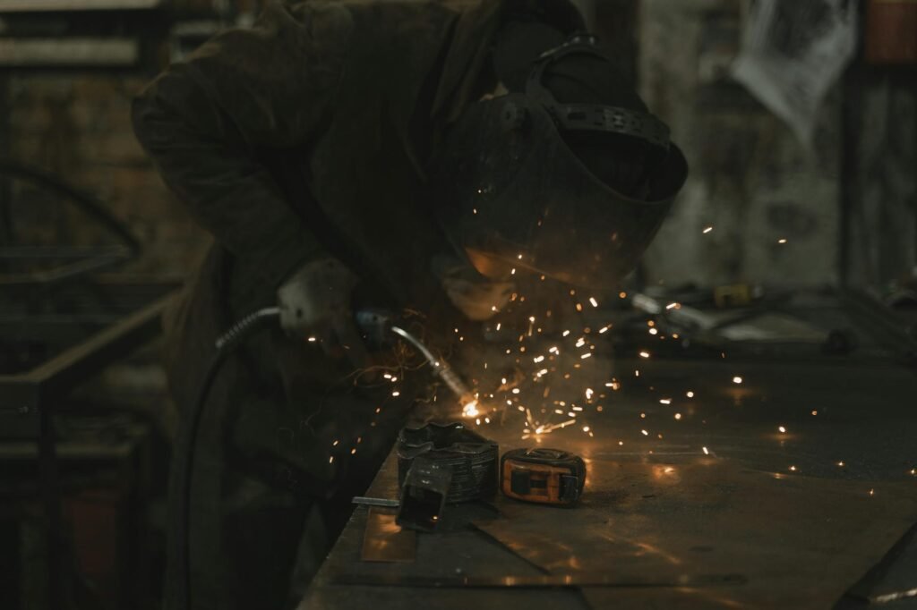 A welder skillfully operates in a dimly lit workshop, surrounded by sparks.