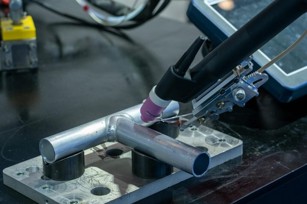Detailed view of metal welding apparatus in action on industrial workbench.