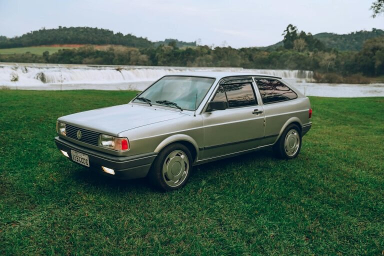 Vintage car parked by lush green landscape and waterfall in Coronel Vivida, Brazil.