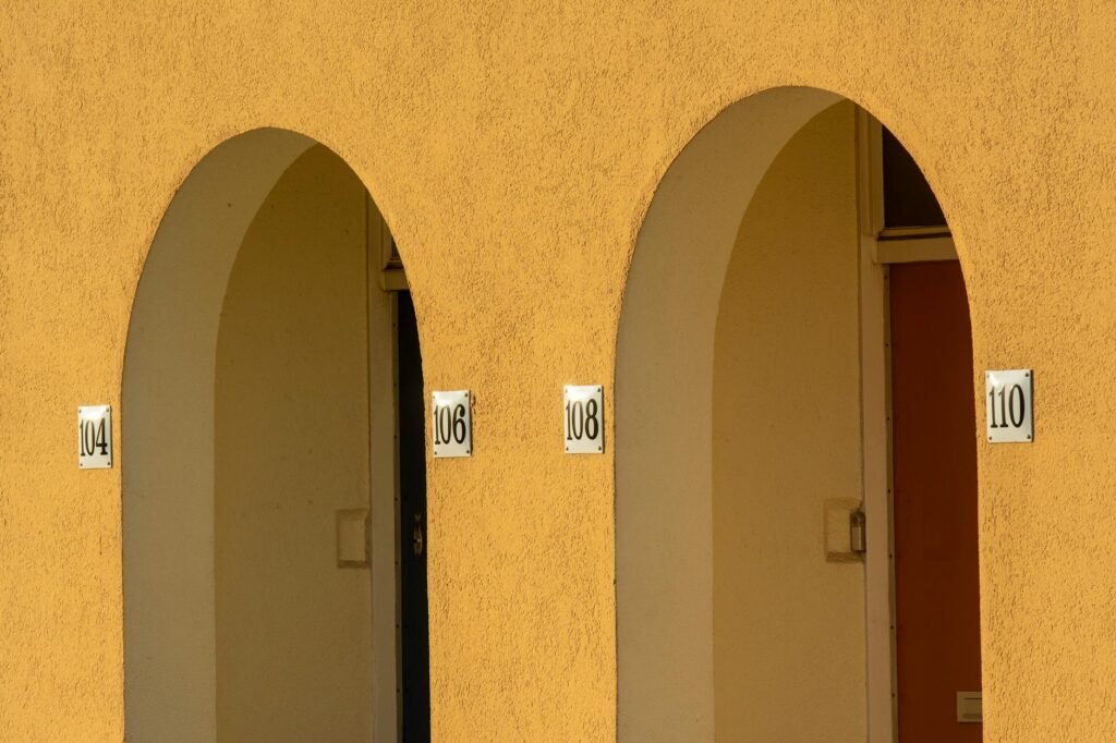 Close-up of yellow arched walls with apartment numbers in an urban setting.