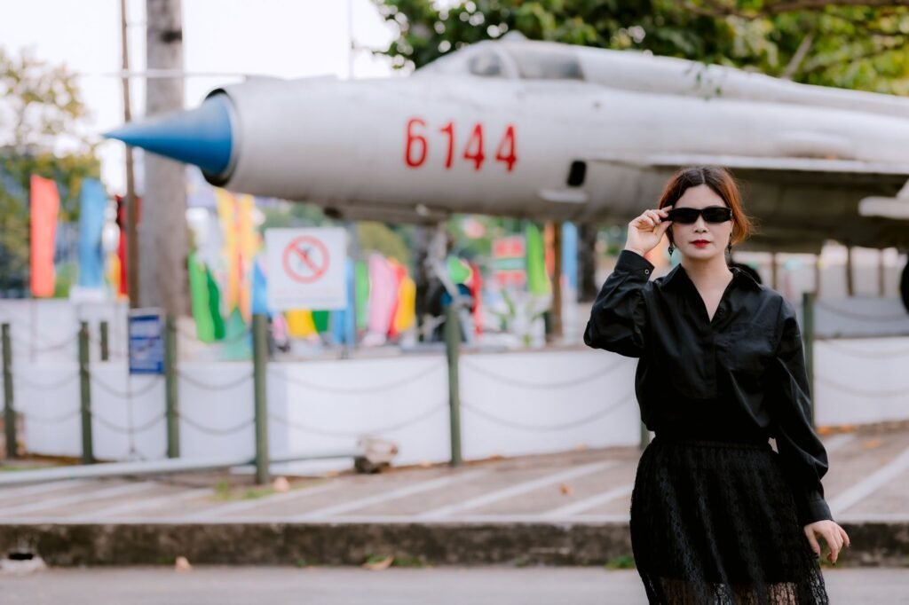 Stylish woman in black by a vintage jet, blending fashion with aviation history.