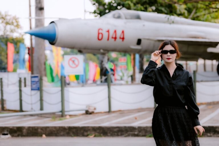 Stylish woman in black by a vintage jet, blending fashion with aviation history.