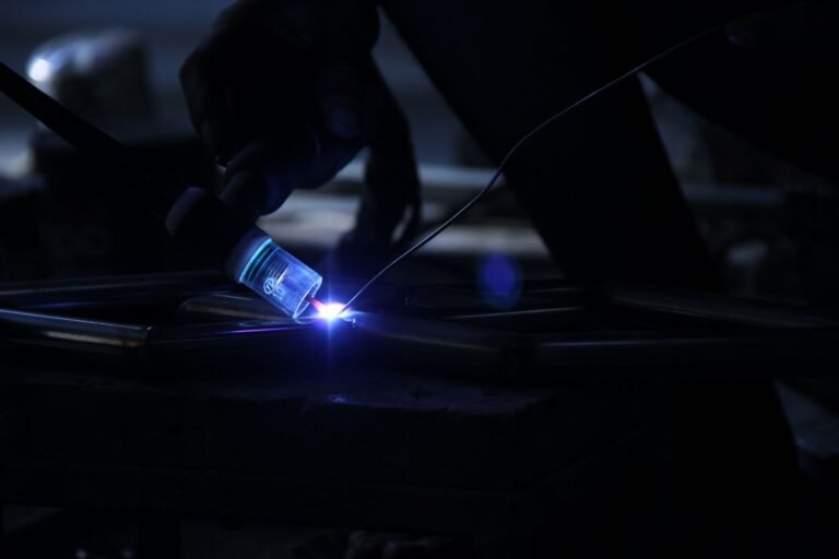Intense close-up of a welding process in a dark industrial setting, showcasing sparks and precision.