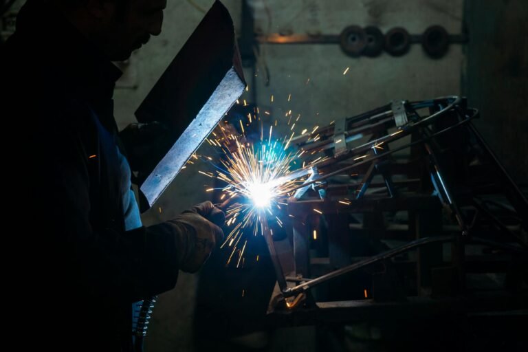 A skilled welder uses a torch to work on metal in an industrial workshop setting.