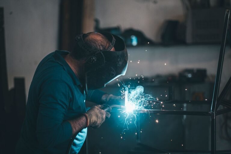A skilled welder works with precision, creating sparks during metal fabrication in an industrial workshop.