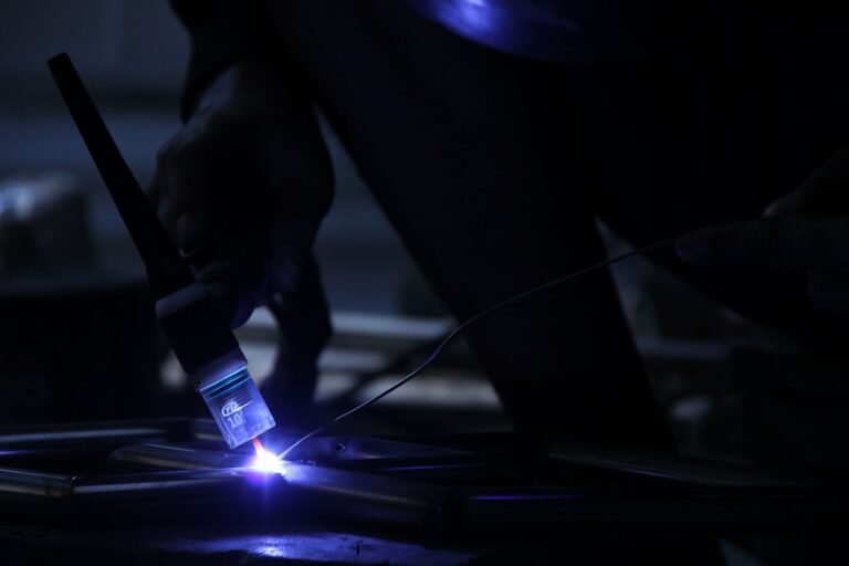 Close-up shot of a welder working in a dimly lit industrial environment.