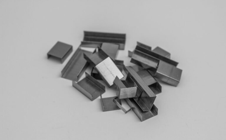 A monochrome photo of metal staples scattered on a grey surface, ideal for office concepts.